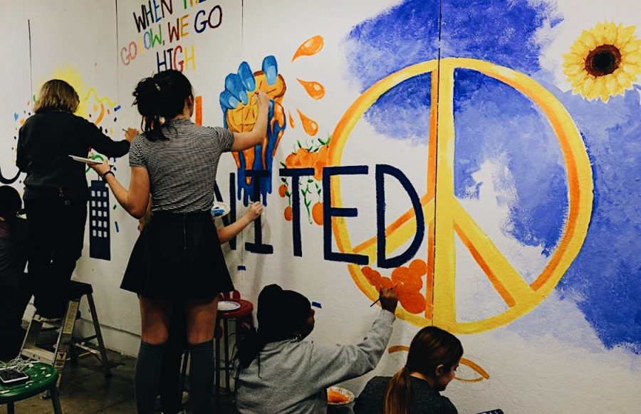 Syracuse students painting a mural over the graffiti. 
